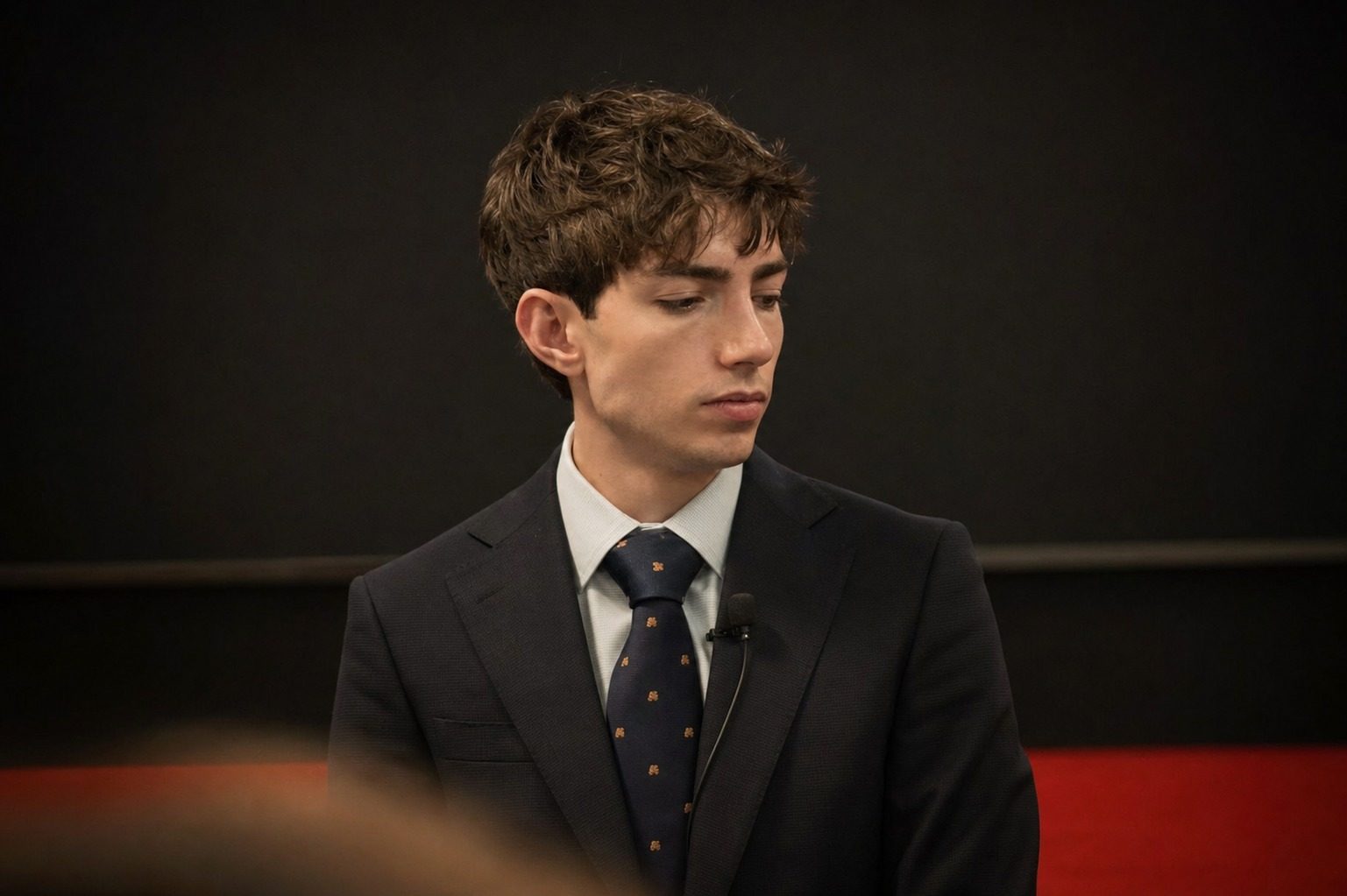 Hartley Charlton, technology journalist, speaking on camera in a suit with a lapel microphone